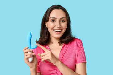 Beautiful young woman with vibrator on blue background