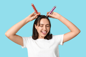 Funny young woman with vibrators on blue background