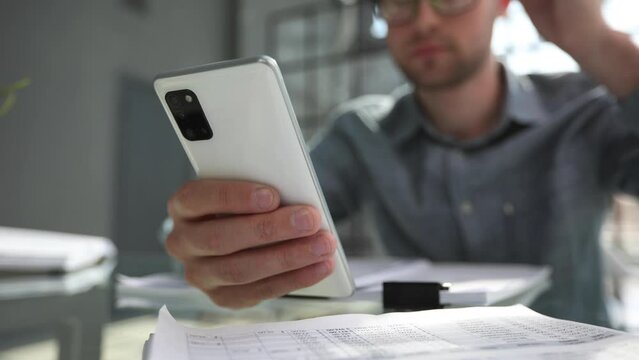 uses smrt phone for making calls or reading news online. Businessman reviews documents