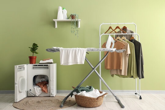 Interior of laundry room with ironing board, clothes rack and dryer machine