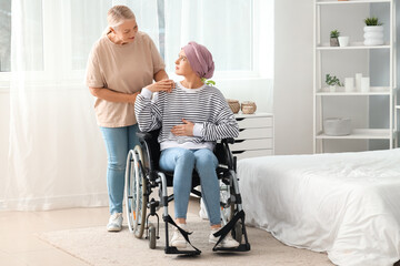 Fototapeta na wymiar Young woman after chemotherapy in wheelchair with her mother at home. Stomach cancer concept