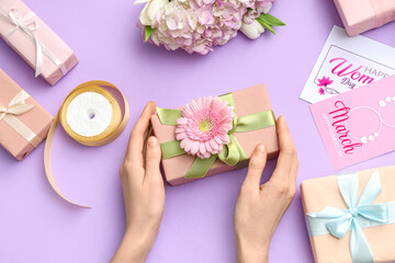 Female hands with gift boxes and cards on purple background. International Women's Day