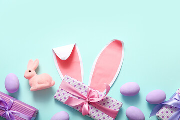 Paper bunny ears with Easter eggs and gift boxes on turquoise background