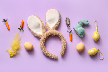 Bunny ears with Easter eggs and carrots on lilac background