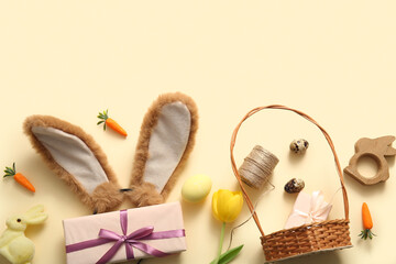 Easter composition with bunny ears, painted eggs and wicker basket on beige background