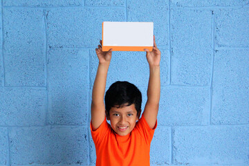 10 year old dark-skinned Latino boy shows a box of a new video game or toy very excited and happy