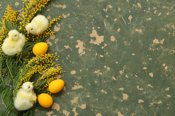 Beautiful Easter composition with painted eggs, chickens and mimosa on green table