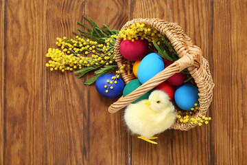 Cute chicken and basket with Easter eggs on  wooden table