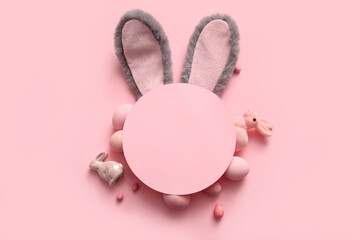 Bunny ears with Easter eggs and blank greeting card on pink background