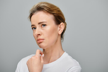 upset good looking woman with contact lenses and collected hair looking away on gray backdrop