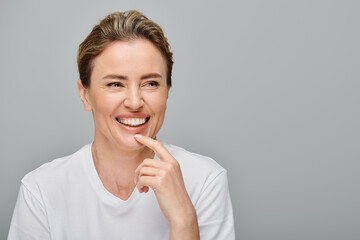 cheerful attractive woman with blonde collected hair and contact lenses smiling and looking away