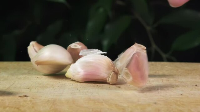 pieces of unpeeled garlic fall on the table, slow motion, proper nutrition, ghee falls on the table