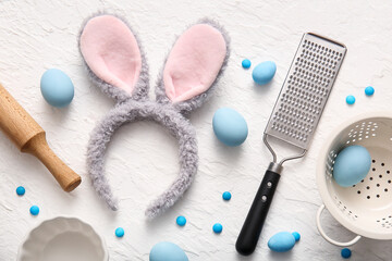 Fototapeta na wymiar Bunny ears with Easter eggs and cooking utensils on white grunge background
