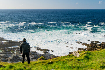 Tourist admiring scenic beauty of Malin Head, Ireland's northernmost point, Wild Atlantic Way, spectacular coastal route. Wonders of nature. Co. Donegal