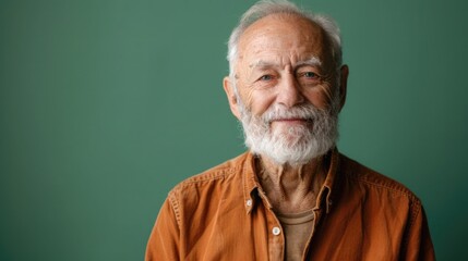 Elderly gentleman with a beard on a soft green background, showing a wise smile, dressed in a classic button-up shirt