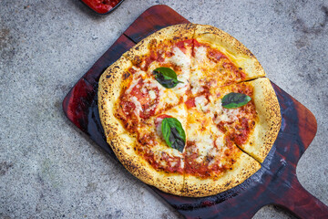 Neapolitan pizza margarita from a local restaurant. Napoleon Italian Pizza with fresh mozzarella and basil. Served on a cutting board with fried potatos and hot sauce