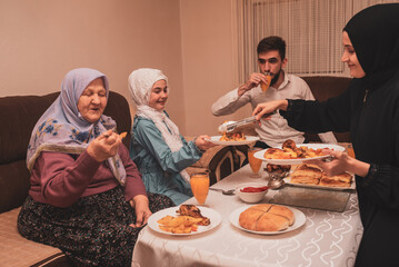 Happy Muslim family having iftar dinner during Ramadan dining table at home.