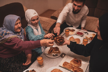 Happy Muslim family having iftar dinner during Ramadan dining table at home.