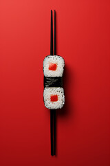 Fresh sushi with chopsticks on red background, minimalistic close-up,copy space,vertically,top view - obrazy, fototapety, plakaty