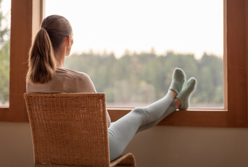 Young thoughtful woman relaxing at home  looking out her window early morning 