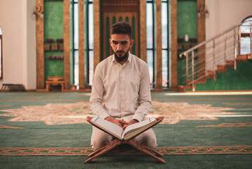 Muslim man praying in mosque and reading Quran - obrazy, fototapety, plakaty