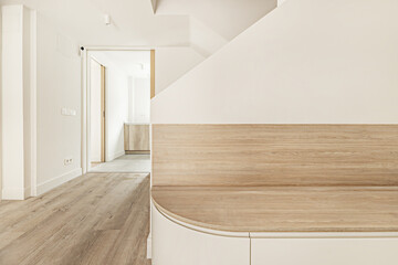 Hallway of a single-family home with a wooden seat with large drawers underneath next to some brick stairs