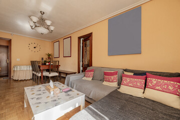 A living room with a gray fabric sofa and a wooden dining table with chairs in a corner