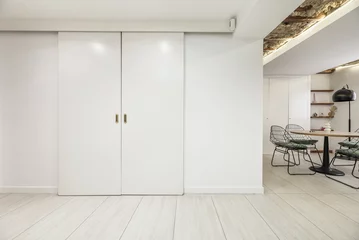 Fotobehang White wooden sliding doors to a room in an industrial loft apartment. © Toyakisfoto.photos