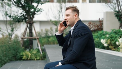 Side view of businessman sitting at park while talking to investors about marketing strategy....