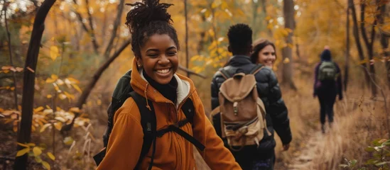 Fototapeten Smiling multiethnic teens holding hands while hiking in fall woods. © Sona