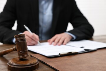 Man signing document in lawyer's office, focus on gavel
