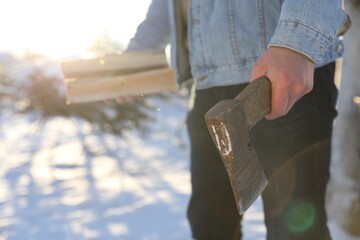 Man with axe and wood outdoors on sunny winter day, closeup. Space for text