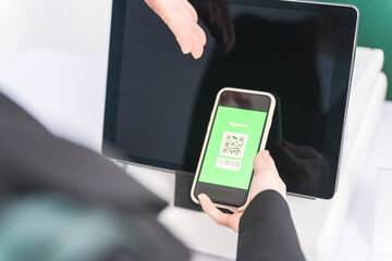 スマホで電子マネーを使って電子決済・モバイル決済・キャッシュレス決済・タッチレス決済をする女性
