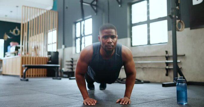 Man, fitness and push ups in workout, strength or exercise on floor for endurance at gym. Active male person, bodybuilder or athlete lifting body weight in muscle gain, chest or biceps at health club