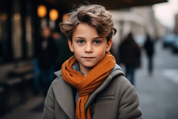 Portrait of a cute little boy in a coat and scarf on the street.
