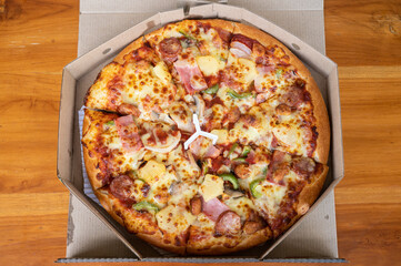A mixed deluxe pizza in paper box.
