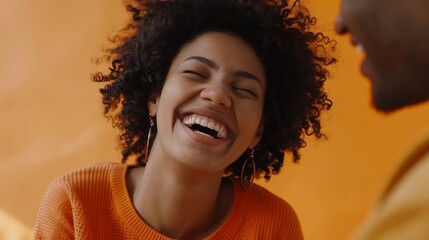 Glad overemotive dark skinned lady with curly hairstyle laughs happily expresses sincere emotions being amused by friend dressed in orange casual jumper models in studio alone with moc : Generative AI
