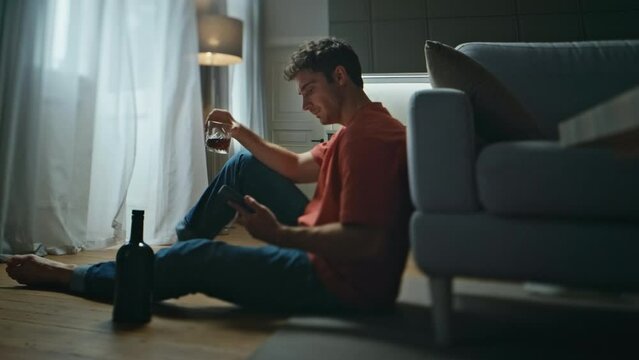 Lonely alcoholic drinking whiskey glass alone in room. Breakup man waiting sms