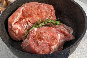 Raw pork meat in saute pan with non-stick coating before baking in oven.