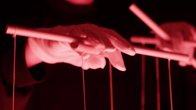 The puppeteer controls the puppets in the theater in red neon light close-up. Managing people at work, in politics and government. Action control