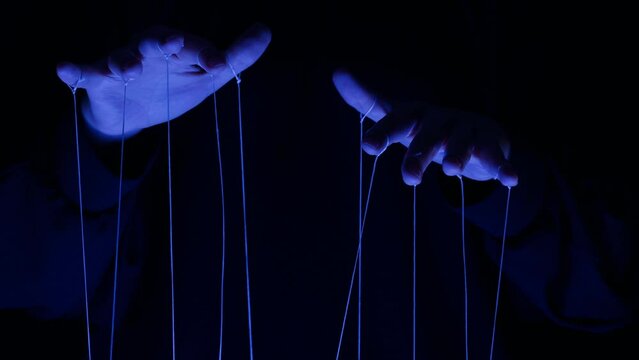The puppeteer controls the puppets in the theater in blue neon light close-up. Managing people at work, in politics and government. Action control