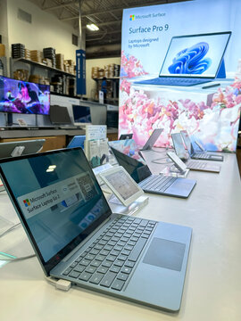 An array of Microsoft Surface Pro 9 laptops on display at a Best Buy electronics store, emphasizing modern technology retail.
