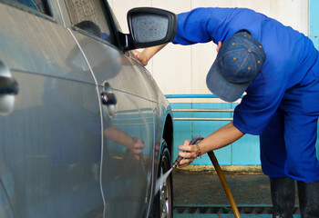a male car wash employee washing the wheels of a vehicle