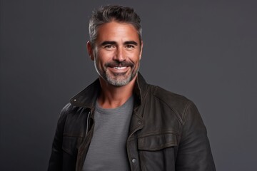 Portrait of a handsome mature man in a leather jacket on a grey background. - obrazy, fototapety, plakaty