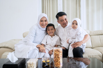 Happy Muslim family sitting together on the couch in the living room.