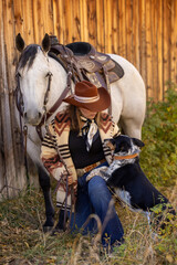 cowgirl with horse and dog barnside