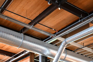 New construction industrial ceiling. Large exposed aluminum ducting and steel beams.