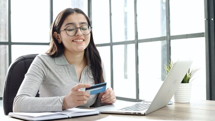 A young woman with glasses checks the card details in close-up