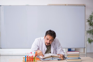 Young male chemist teacher in front of whiteboard