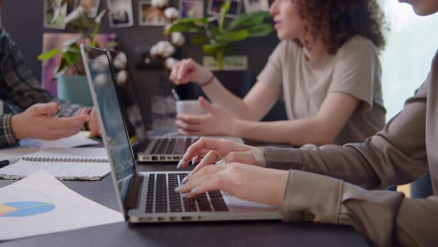 Start up of Creative Young Team Working at the Office. Productive Coworkers Standing at the Table. Successful Team Leader Holding Folder with Graphs. Casual Dressed Collegues Having Meeting.